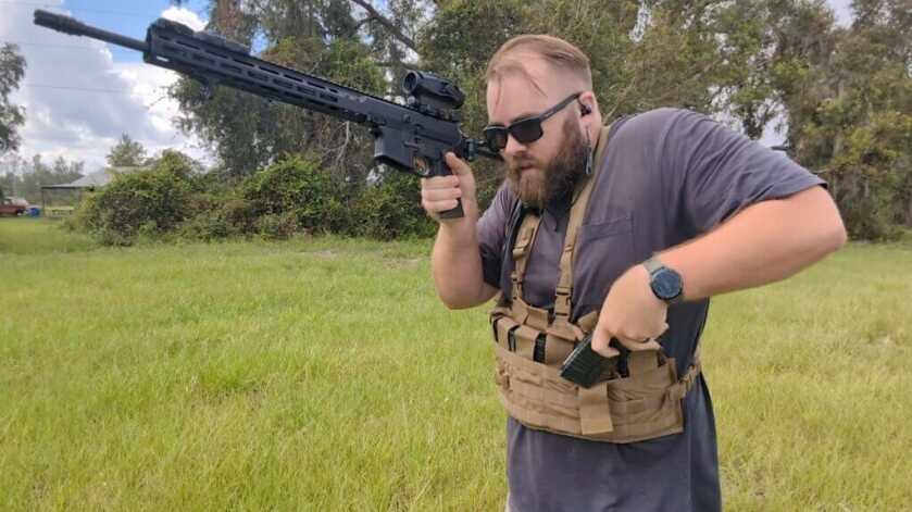 shooter drawing magazine from chest rig.