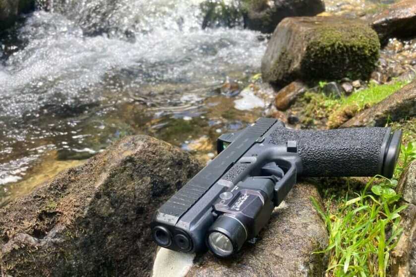 The Streamlight TLR-7 HL-X mounted to a pistol on a mossy rock next to a rushing stream