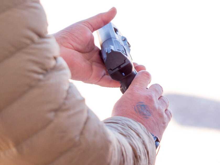 The gun is held in two hands but not in a shooting grip; the ready light shows it is not ready.