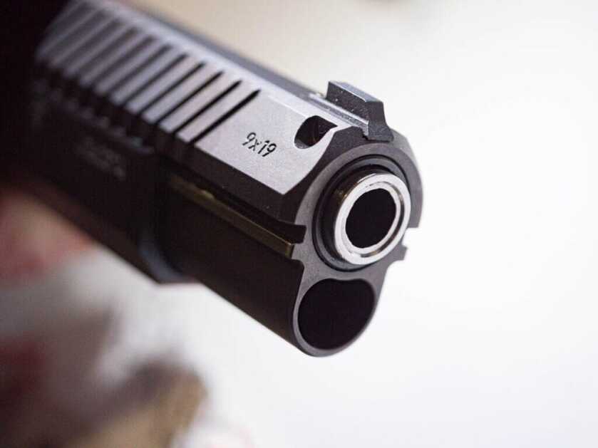 Close up view of the front of the gun showing the end of the barrel and the side of the slide. The dovetail sight is visible too.