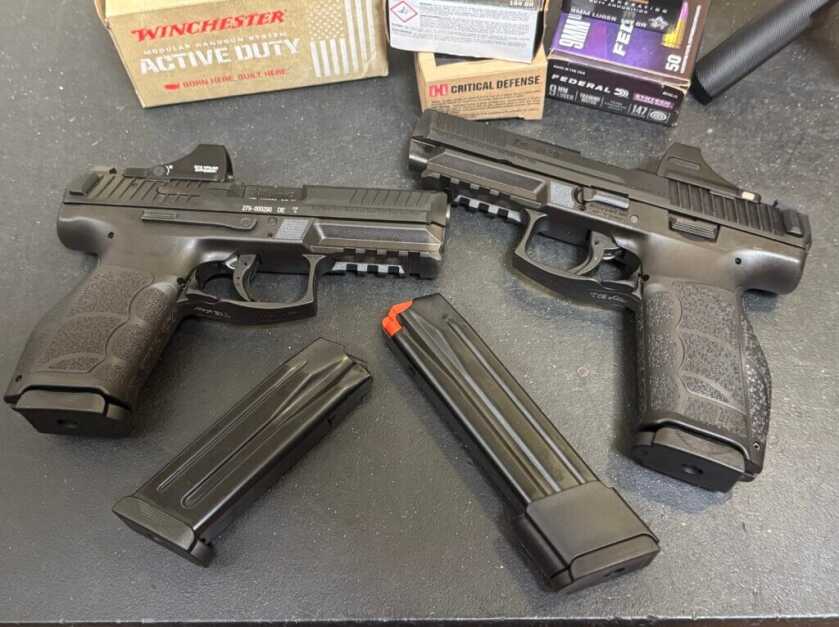 Two black pistols on black counter with two magazines and Winchester ammo boxes