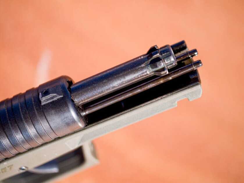 Closeup view of the front of the gun with the slide locked open, looking down from above. The end of the rotary barrel and the guide rods are exposed.