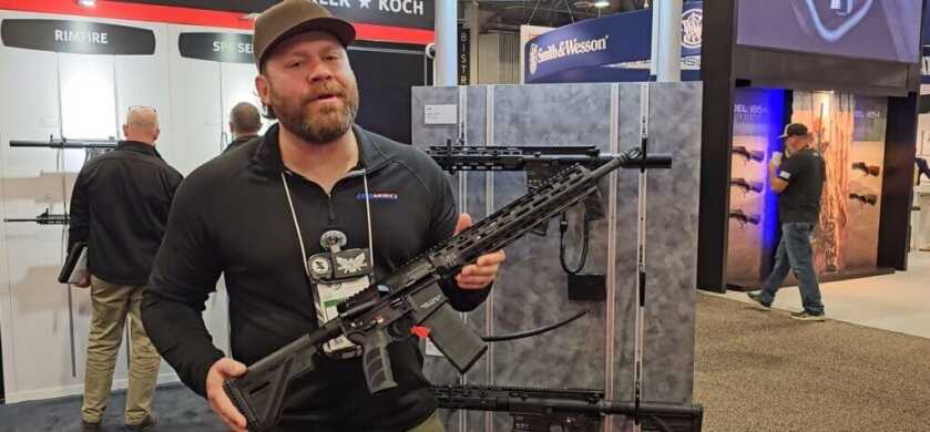 A bearded man holds the new MR556 A4 rifle from HK.