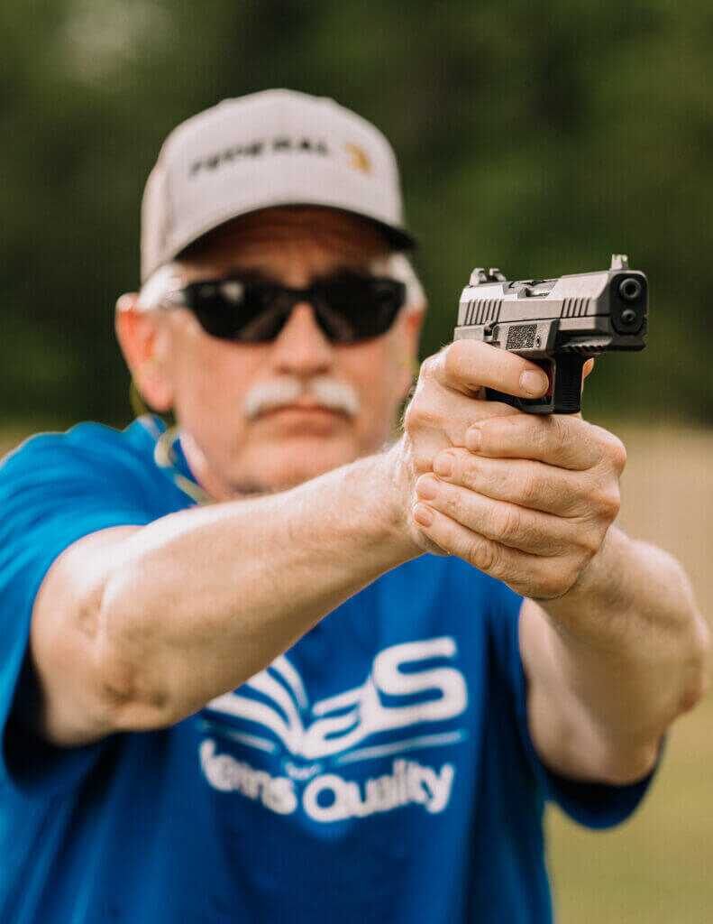 Man in sunglasses and hat aiming handgun 