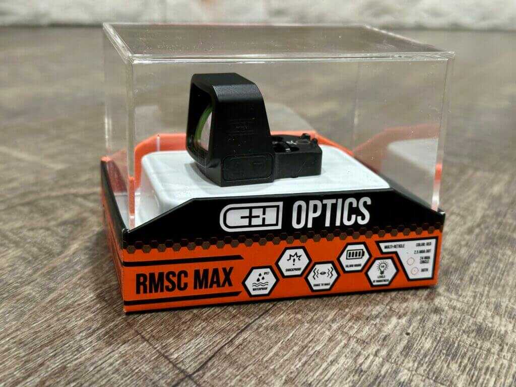 A red dot in its original packaging is posed against a wood floor backdrop. 