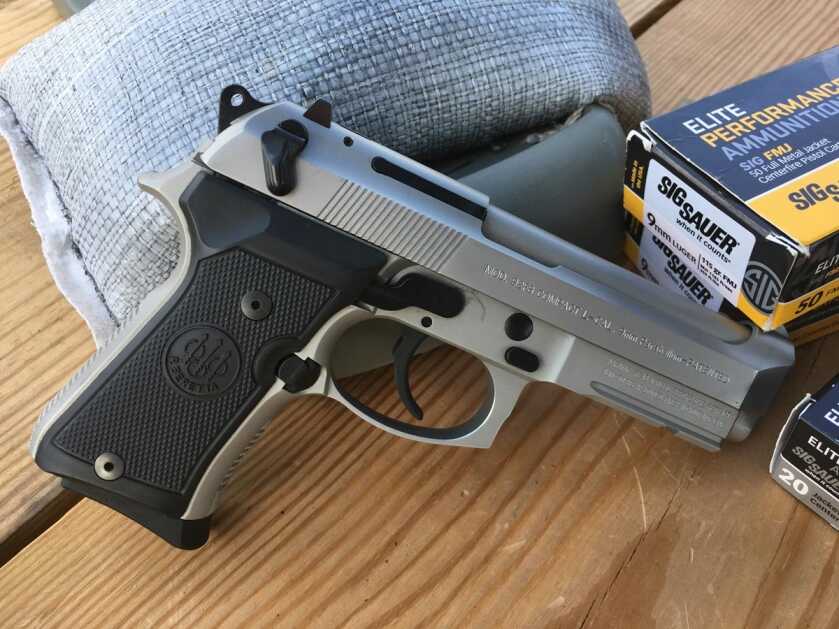 Beretta 92 Compact INOX 9mm pistol on a range bench with ammunition