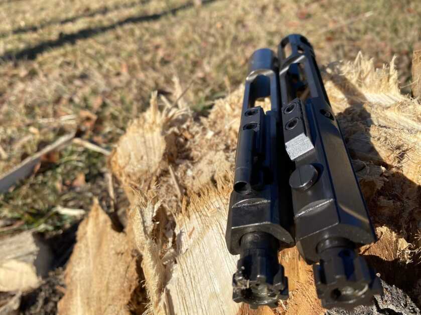 Skeletonized CMMG 5.7x28mm bolt carrier next to a standard AR-15 bolt carrier