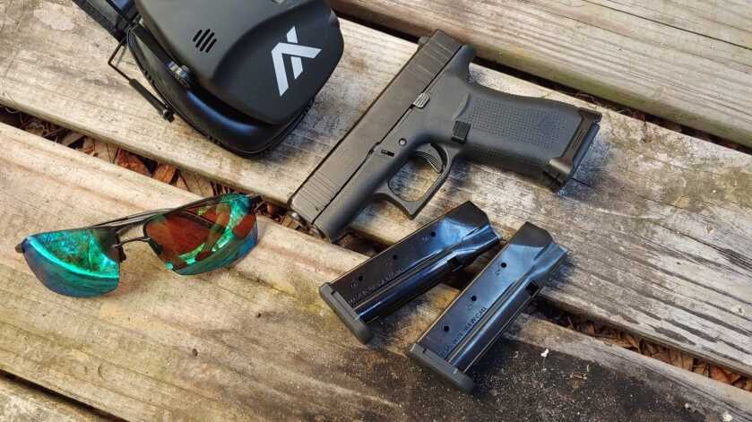 Glock 43X with magazines on a wooden table, best slim grip handgun for small hands 2026