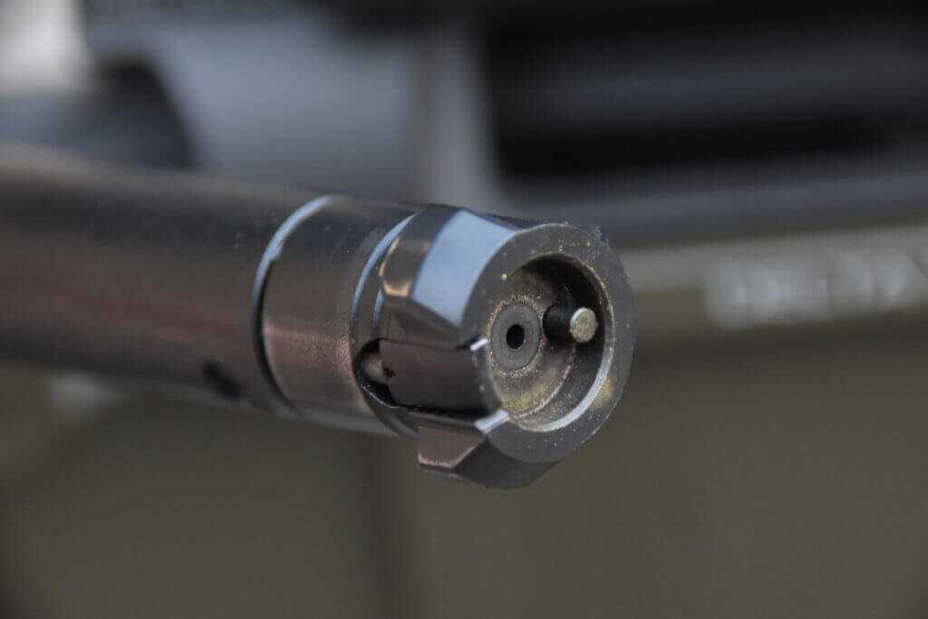 The dirty bolt face of a three-lug rifle bolt is shown.