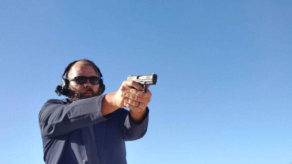 Man in headset and sunglasses aiming pistol