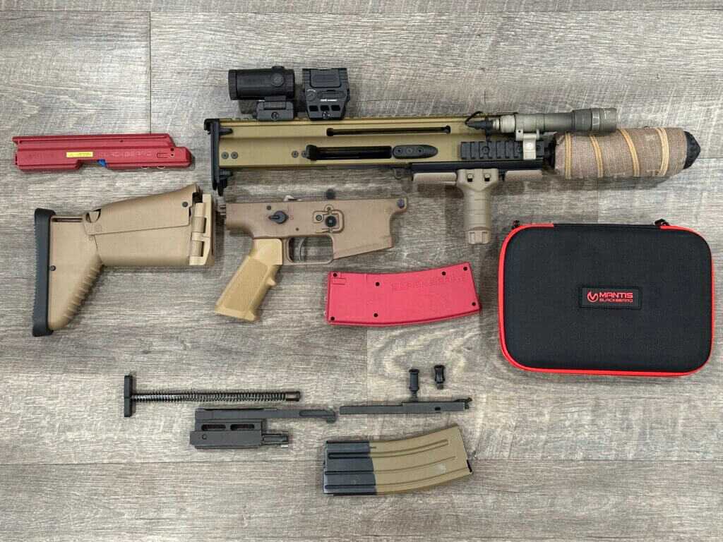 The firearm is completely disassembled with the BlackbeardX training device sitting beside it.