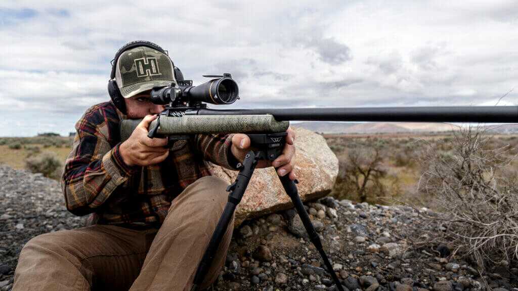 man looking rifle scope[e with rifle on a bipod