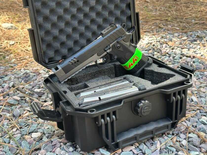 A pistol is staged on top of a black carry case in the outdoors.