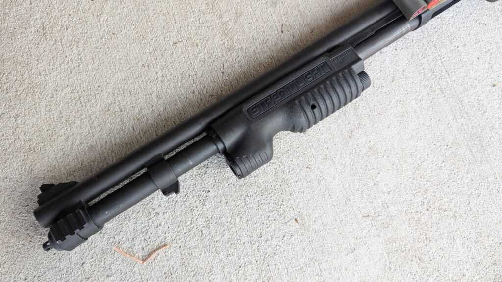 Pump shotgun with integrated forend light showing control placement