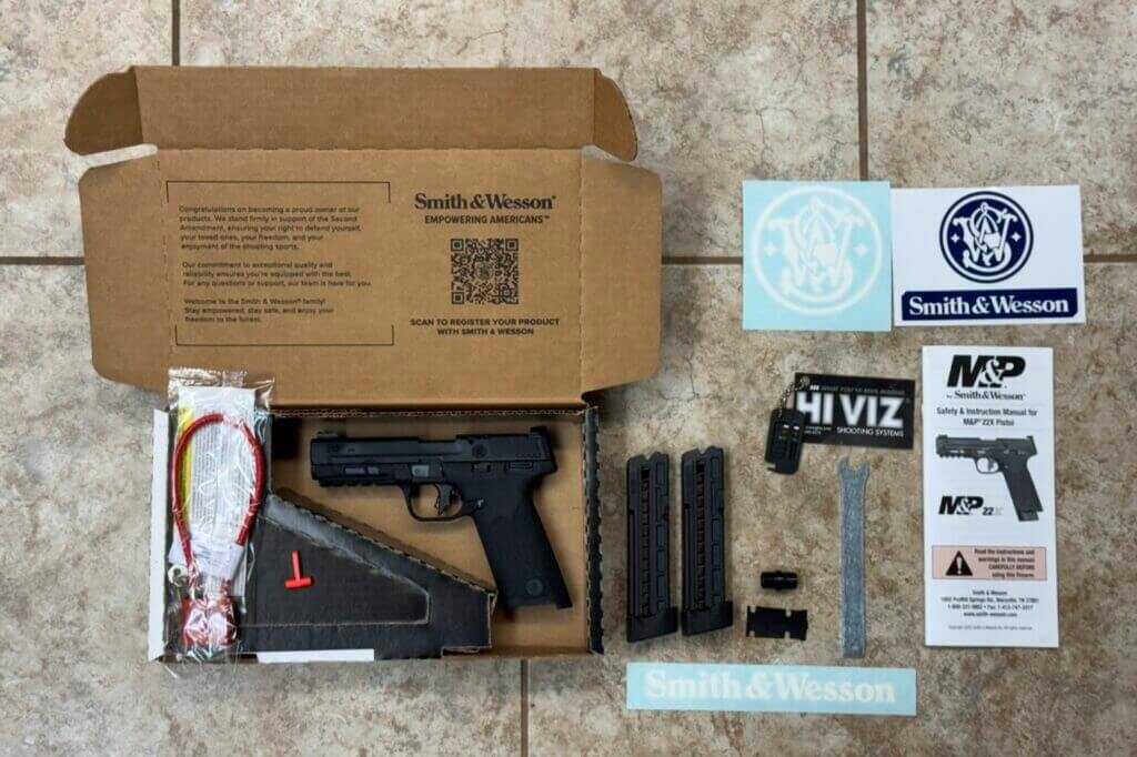M&P22X pistol with two 20 round magazines, optic plate, and 1/2x28 suppressor adapter laid out on table