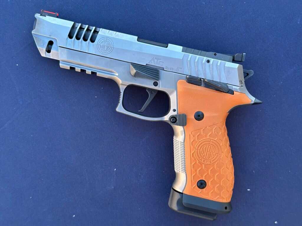 A closeup view of an orange and silver gun on a blue table.