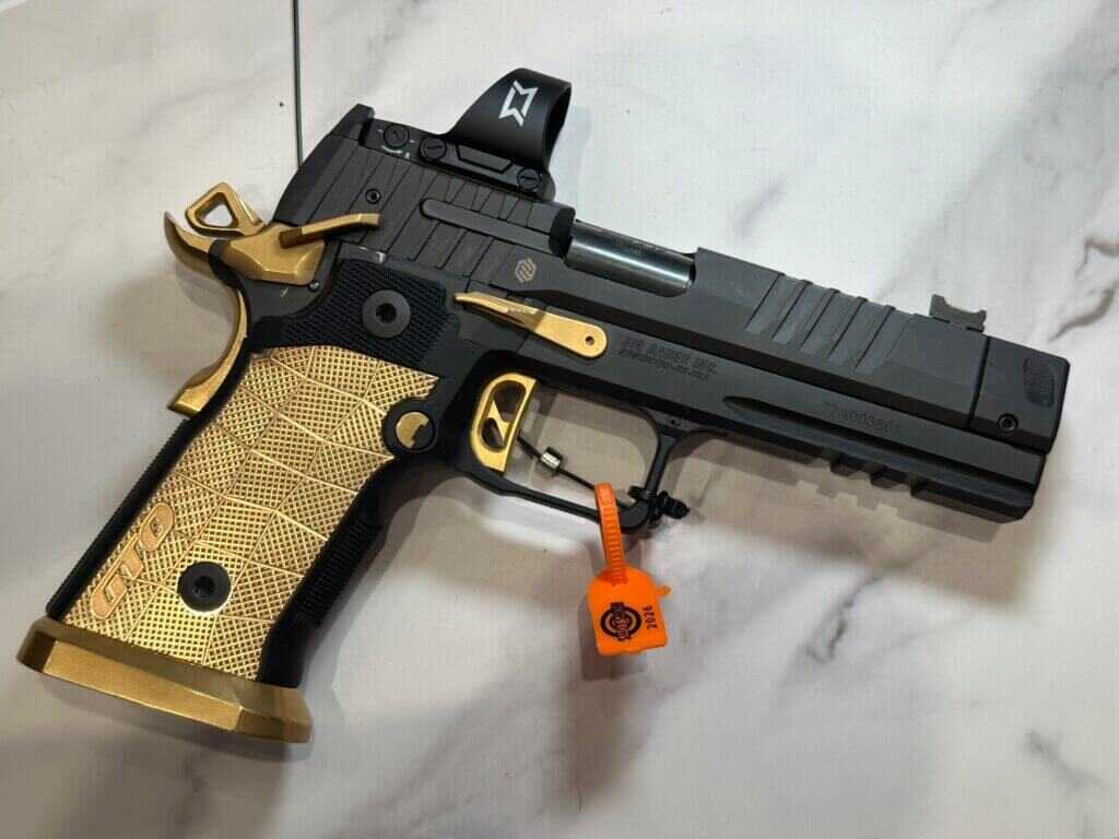 A black pistol with brass accents rests on a granite counter.