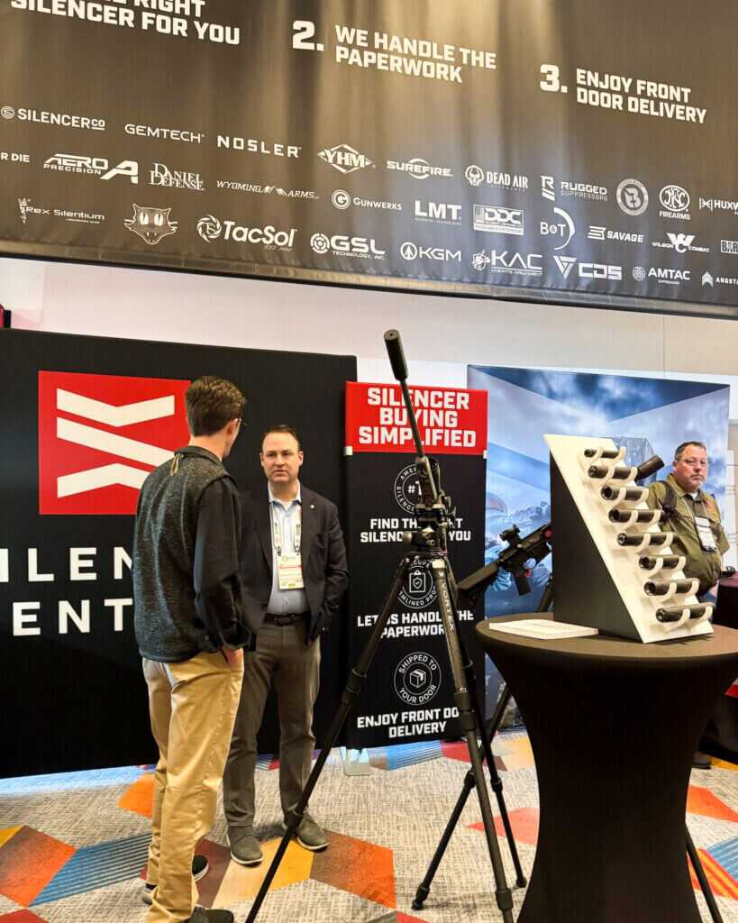 Suppressed rifle on a stand at a show booth highlighting Silencer Central’s products