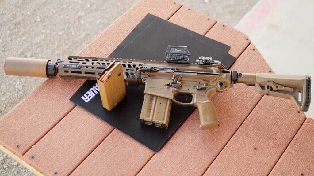 The whole gun lying on a black matt on a shooting table at the range. The gun is facing left with the left side visible.