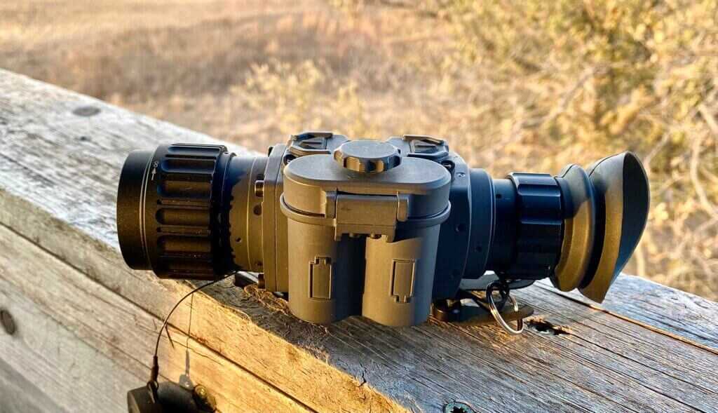 Armasight Warden 640 thermal monocular resting on a wooden rail overlooking West Texas brush country