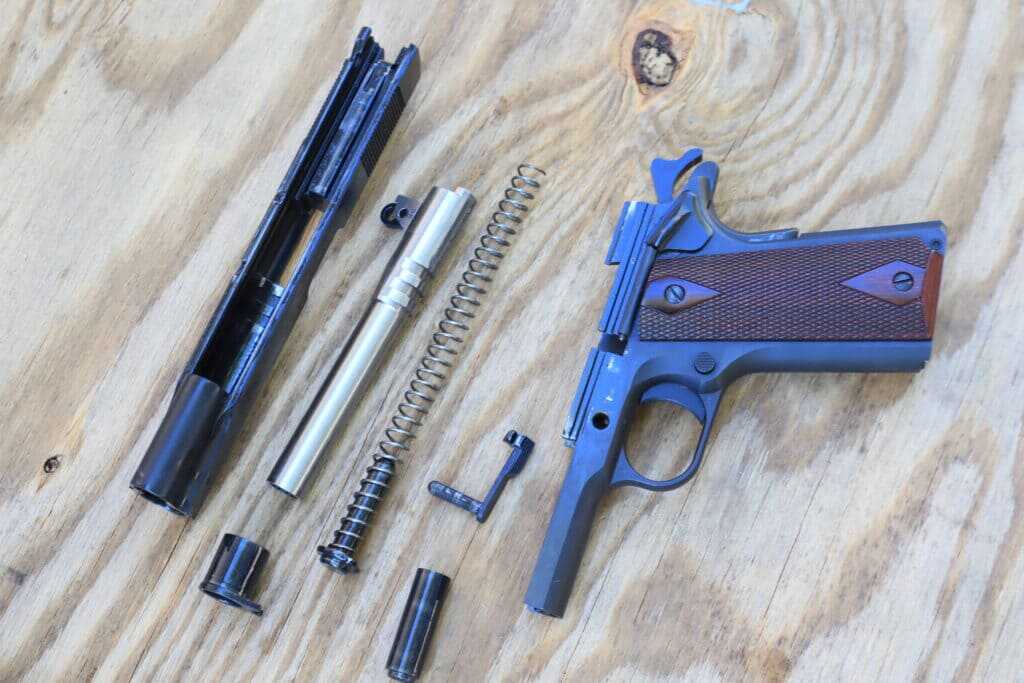 Disassembled Colt Government Model .45 ACP Series 70 1911 showing slide, frame, barrel, guide rod, and recoil components