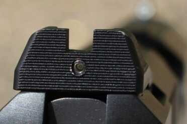 That small spot glows, but is smaller than the white spot on the front, so you won't mistake the two in the dark.