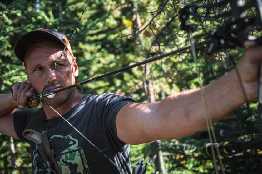 Father's Day Gift Guide Hunter sighting an arrow and bow