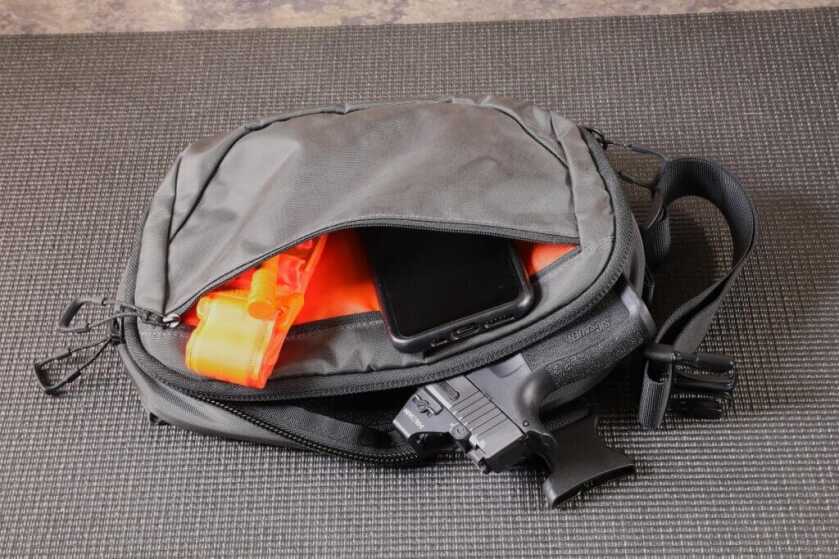 Black Low Viz Waist Pack holding cell phone and tourniquet