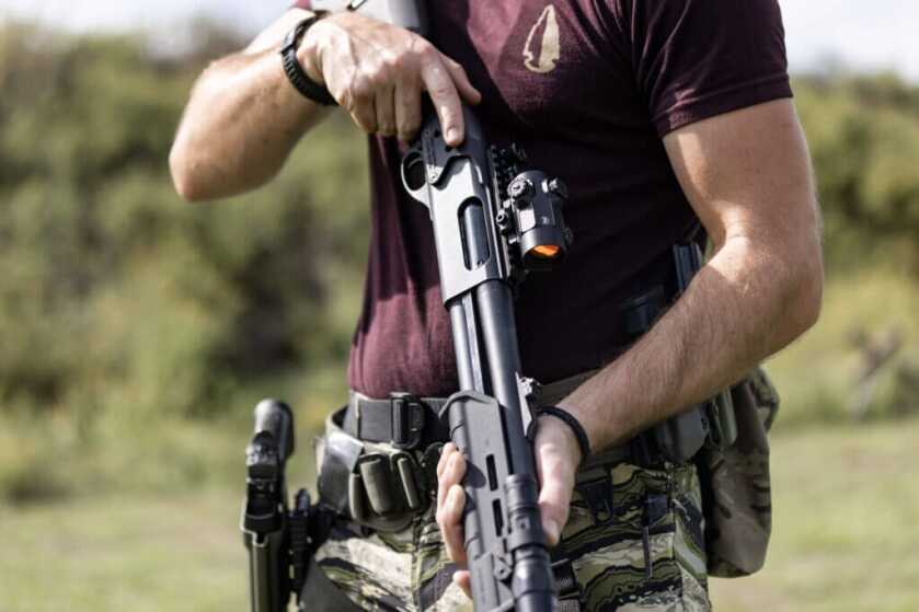 Man in camo pants holding gun with small optic