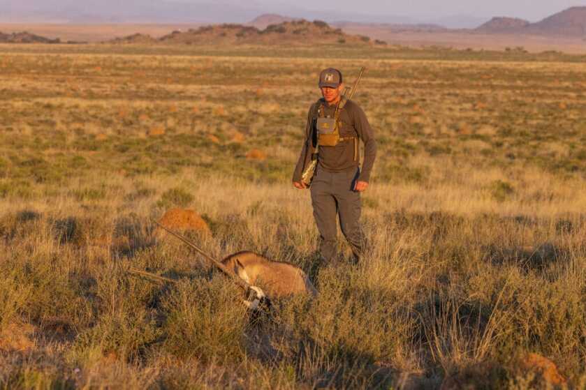 Hunter with exotic animal in grassy Africa field