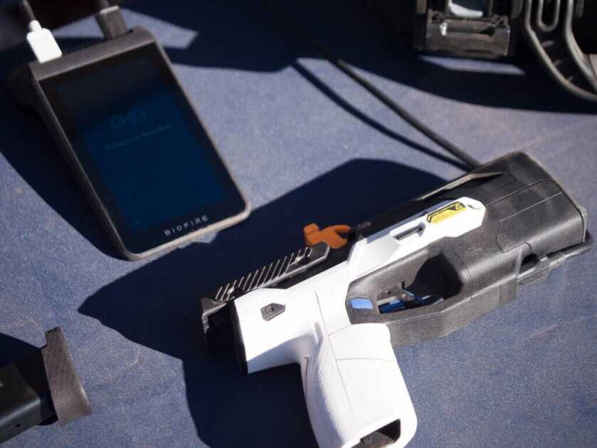 The pistol is laying on the table with its dock. The pistol is facing to the right.