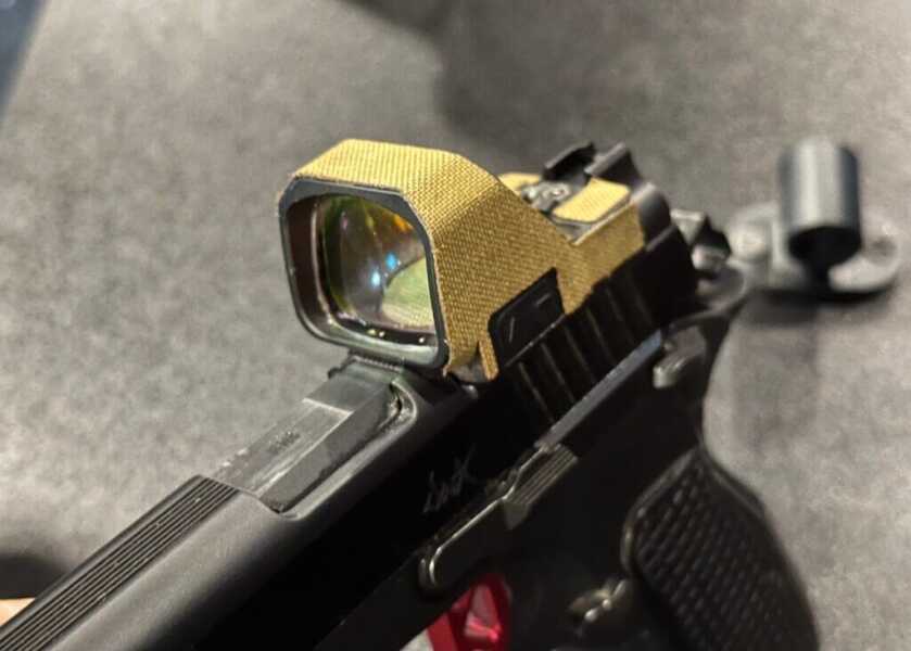 A pistol optic with a large window sits on top of the handgun.