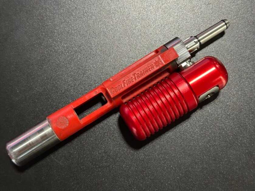 Closeup look from the top down on a red training device that replaces an AR15 bolt.